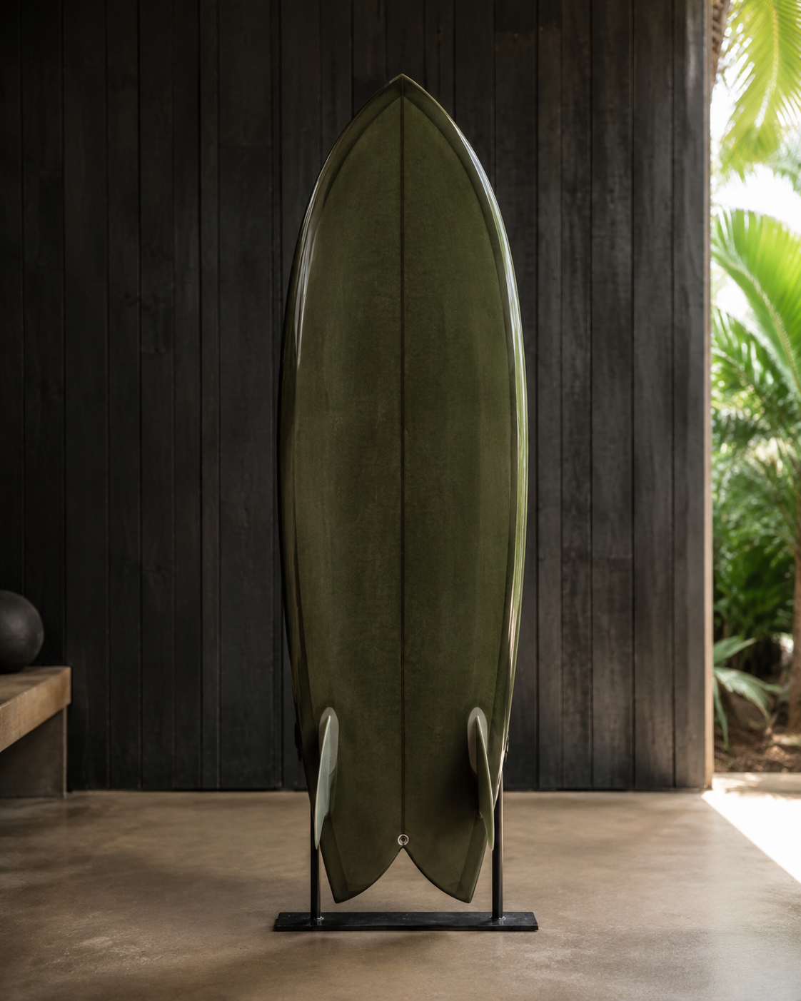 An olive-green twin-fin fish with a swallow tail, standing on a rack against dark timber.